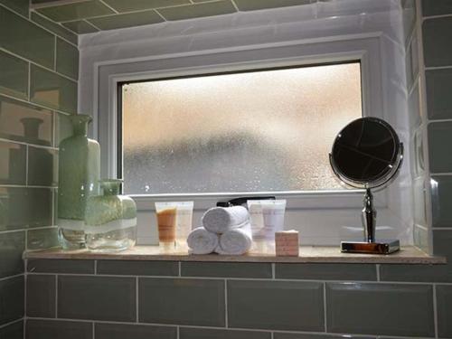 马尔文维尔Kitts Cottage的浴室窗户配有带毛巾和镜子的架子