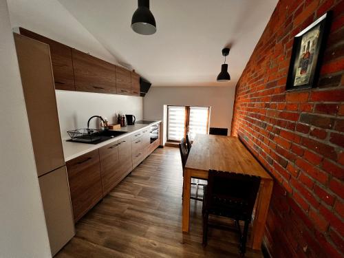 斯凯尔涅维采Apartamenty na 1 Maja的厨房设有砖墙和木桌