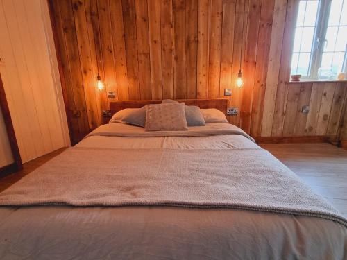 埃克塞特Pass the Keys Charming 19th century country cottage for 2 guests的木墙客房内的一张大床