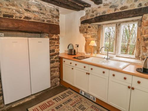 ManserghBeckside Cottage的厨房配有白色橱柜、水槽和窗户。