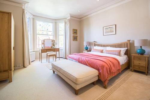 伦敦Homely 2 Bedroom Victorian Apartment in Hampstead的卧室配有1张床、1张桌子和1把椅子