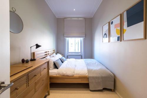 伦敦Homely 2 Bedroom Victorian Apartment in Hampstead的一间卧室配有一张床和一个木制梳妆台