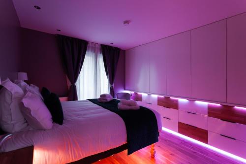 尚蒂伊Suite Appart Place Versepuy的紫色卧室配有一张带灯的床铺