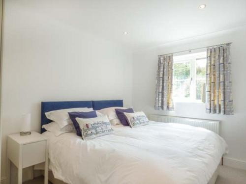 圣梅尔林7 Harlyn Cottages的卧室配有带枕头的白色床和窗户。