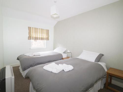 Santon BridgeWilliam Court Cottage的两张位于酒店客房的床,配有毛巾