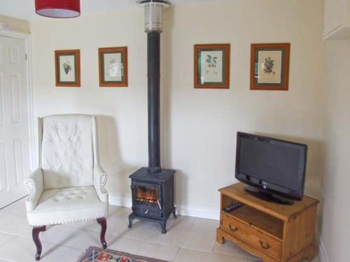 WortleyHollins Wood Bothy的客厅配有电视、椅子和炉灶。