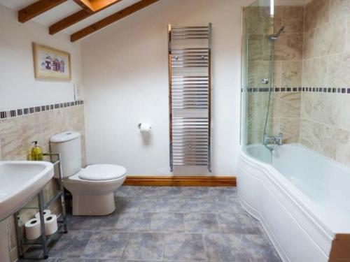 DunningtonThe Barn Ivy Cottage的浴室配有卫生间、浴缸和水槽。