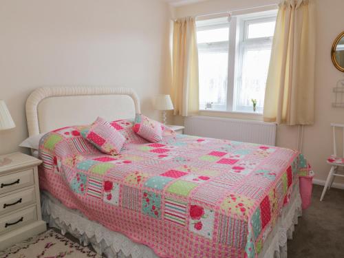CheveleySpurling Cottage的卧室配有粉色和白色的床,设有窗户