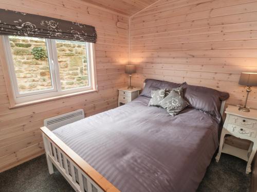 AshoverThorntree Lodge的木制客房内的一间卧室,配有一张床
