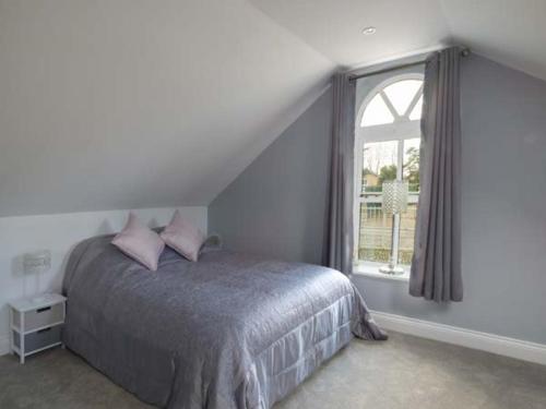 Kingsbourne GreenStudio at Little Trees Farm的一间卧室配有带粉红色枕头的床和窗户。