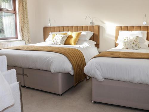 CoreleyWrens Nest的一间卧室配有两张带白色床单和金色枕头的床。