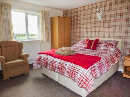 埃尔斯米尔The Willows的一间卧室配有一张带红色枕头的床和一把椅子