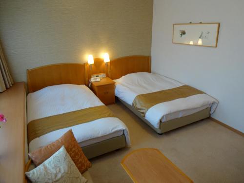 神户神户流明酒店的酒店客房设有两张床和一张桌子。