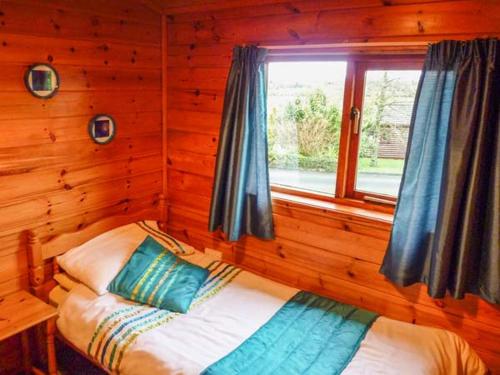 GlenCabin 2的木制客房的一张床位,设有窗户