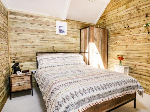 纽基Barn Acre Cottage的一间卧室设有木墙和床