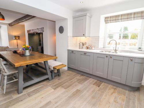 阿贝尔格莱Llys Alaw的厨房配有白色橱柜和木桌