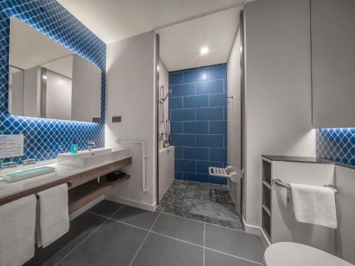 长春长春净月智选假日酒店的浴室设有水槽和蓝色瓷砖淋浴。