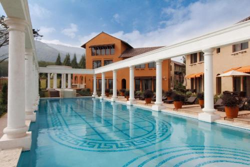 慕斯Toscana Hotel La Casetta的一座大游泳池,位于一座有柱子的房子前