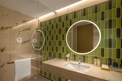 青岛青岛金水套房假日酒店的绿色瓷砖浴室设有水槽和镜子