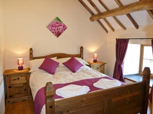 阿贝尔格莱Beudy Bach的一间卧室配有一张带紫色枕头的大床