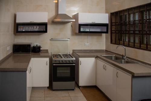 阿克拉RESIDENCE IVOIRE的厨房配有白色橱柜、炉灶和水槽。