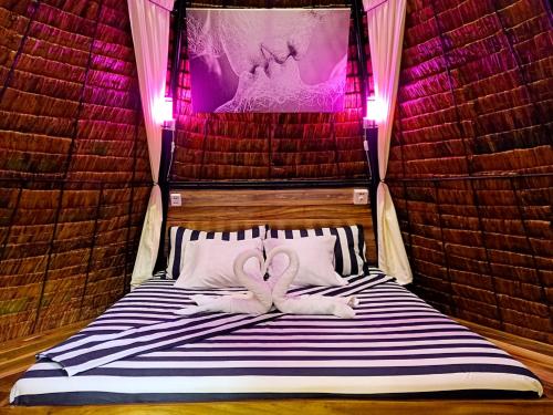 莫阿尔博阿Archery-Asia Nipa Huts Moalboal的粉红色灯的房间床上的两条毛巾