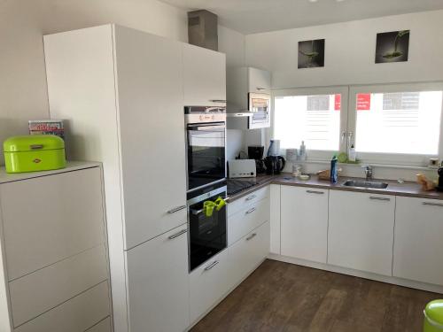 卡德赞德Tin Tin in Cadzand, Koolse Hoeve 1b的厨房配有白色橱柜和黑烤箱。