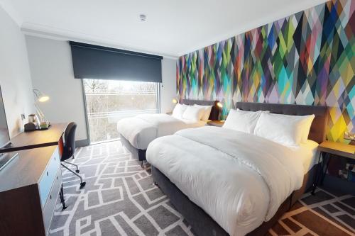 布拉克内尔Village Hotel Bracknell的酒店客房设有两张床和彩色墙壁。