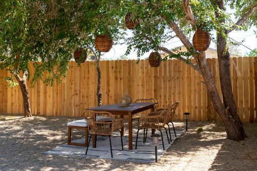 约书亚树Red Rock - Desert feel - Game Room的树下木桌和椅子,有栅栏