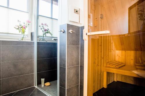 富伦多夫Ferienhaus Schilfrohrsaenger 26的浴室里设有玻璃门淋浴