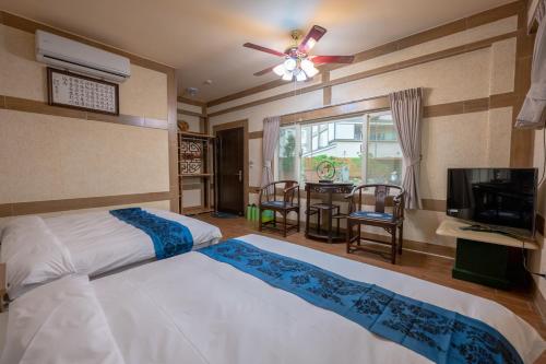 公馆龟树民宿的一间卧室配有一张床、一台电视和一张桌子