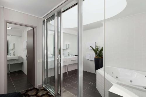 堪培拉Rydges Canberra的一间带玻璃淋浴和浴缸的浴室