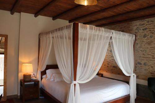 ArocheHotel Palacio Conde del Álamo的卧室配有带白色窗帘的天蓬床