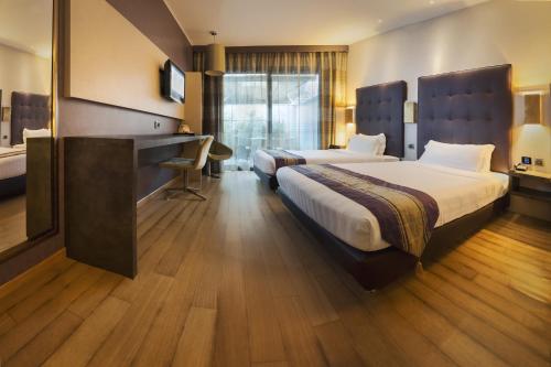 菲乌米奇诺Rome Airport Hotel Fiumicino的酒店客房配有两张床和一张书桌