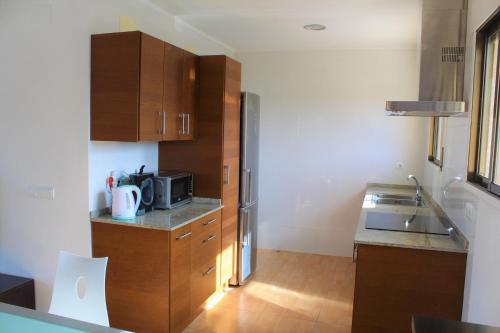 霍斯皮塔勒·德尔英福Apartamento en primera línea de mar的厨房配有木制橱柜和不锈钢冰箱。