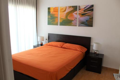 霍斯皮塔勒·德尔英福Apartamento en primera línea de mar的一间卧室配有一张带橙色床单和两盏灯的床。
