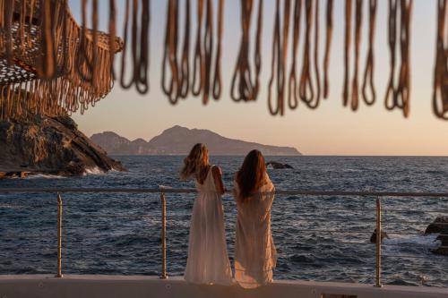 马萨鲁布朗斯Maya Beach Resort的两个女人站在一艘眺望海洋的船上