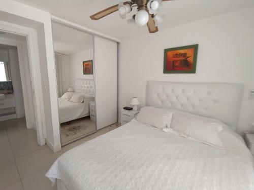 埃斯特角城Apartamento Edificio Unique, Punta del Este的白色的卧室配有白色的床和镜子