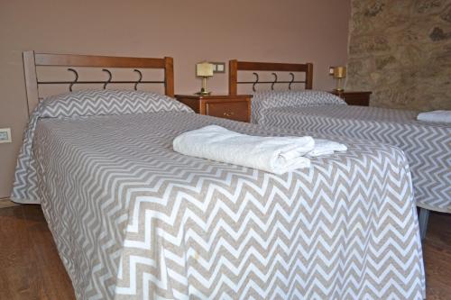 LubiánHotel rural val dos pigarros的两张位于酒店客房的床,配有毛巾