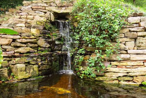 尤里卡斯普林斯BENTON PLACE INN的石墙中的瀑布,带池塘
