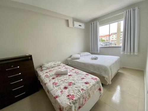 伊列乌斯Vento do Mar - Em frente à PRAIA dos Milionários的一间卧室设有两张床、一个梳妆台和窗户。