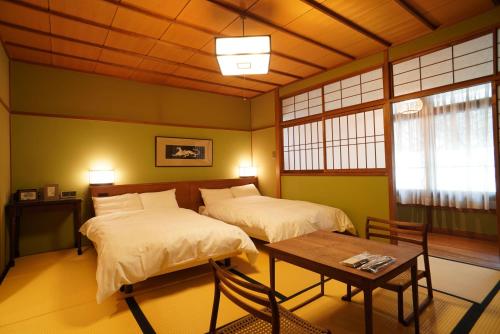 神户有马温泉陶泉御所坊酒店的一间设有两张床和一张桌子的房间
