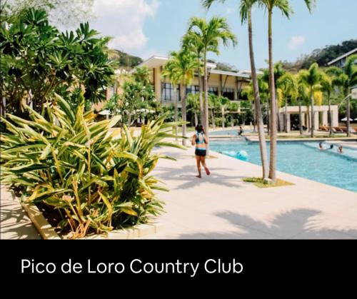 纳苏格布Pico de Loro 2 BD Garden Loft with Lagoon View的一个人在度假村的游泳池旁行走