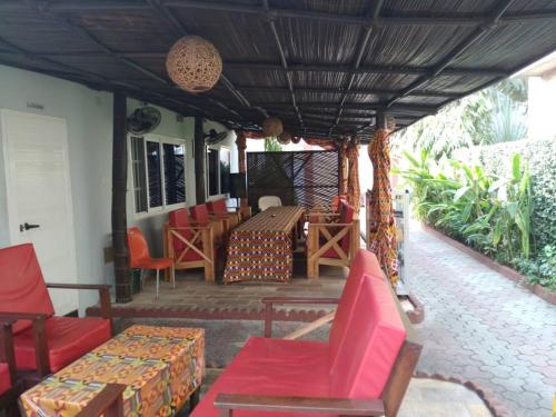 科托努Residence Ivoire Cotonou的门廊配有红色椅子和桌椅