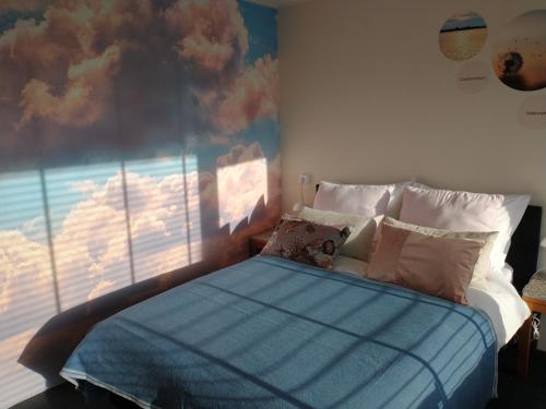 加赫B&Bslapenopeeneiland的一间卧室,配有一张床,画着云彩画