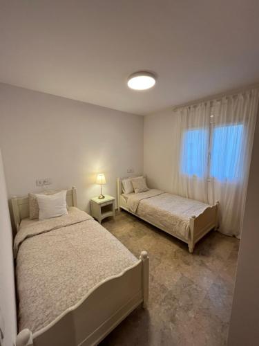 桑特费柳德吉克索尔斯Apartamento luminoso Paloma a 350 metros de la playa con parking gratuito的一间卧室设有两张床、一盏灯和一扇窗户。