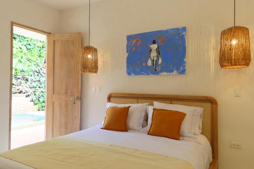 卡塔赫纳Casa Jaguar Hotel Boutique的一间卧室配有带橙色枕头的床和窗户。