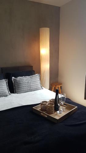 TreignesO'Noire, Viroinval Treignes的床上的托盘,包括一瓶葡萄酒和玻璃杯