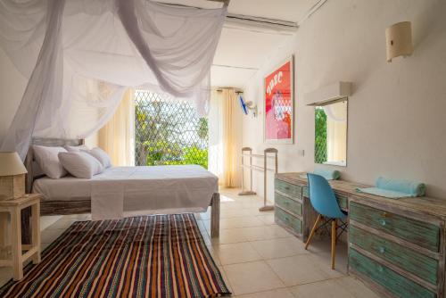 迪亚尼海滩Flamboyant Diani Beach的一间卧室配有一张床、一张书桌和一个窗户。