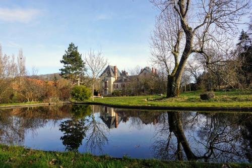 La CelleChâteau de la Combe的公园内的一个池塘,有房子在后面